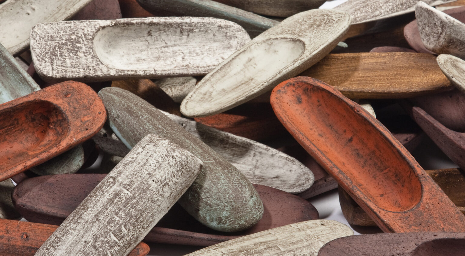 Colorful assortment of small, textured ceramic dishes in various shapes and earthy tones.